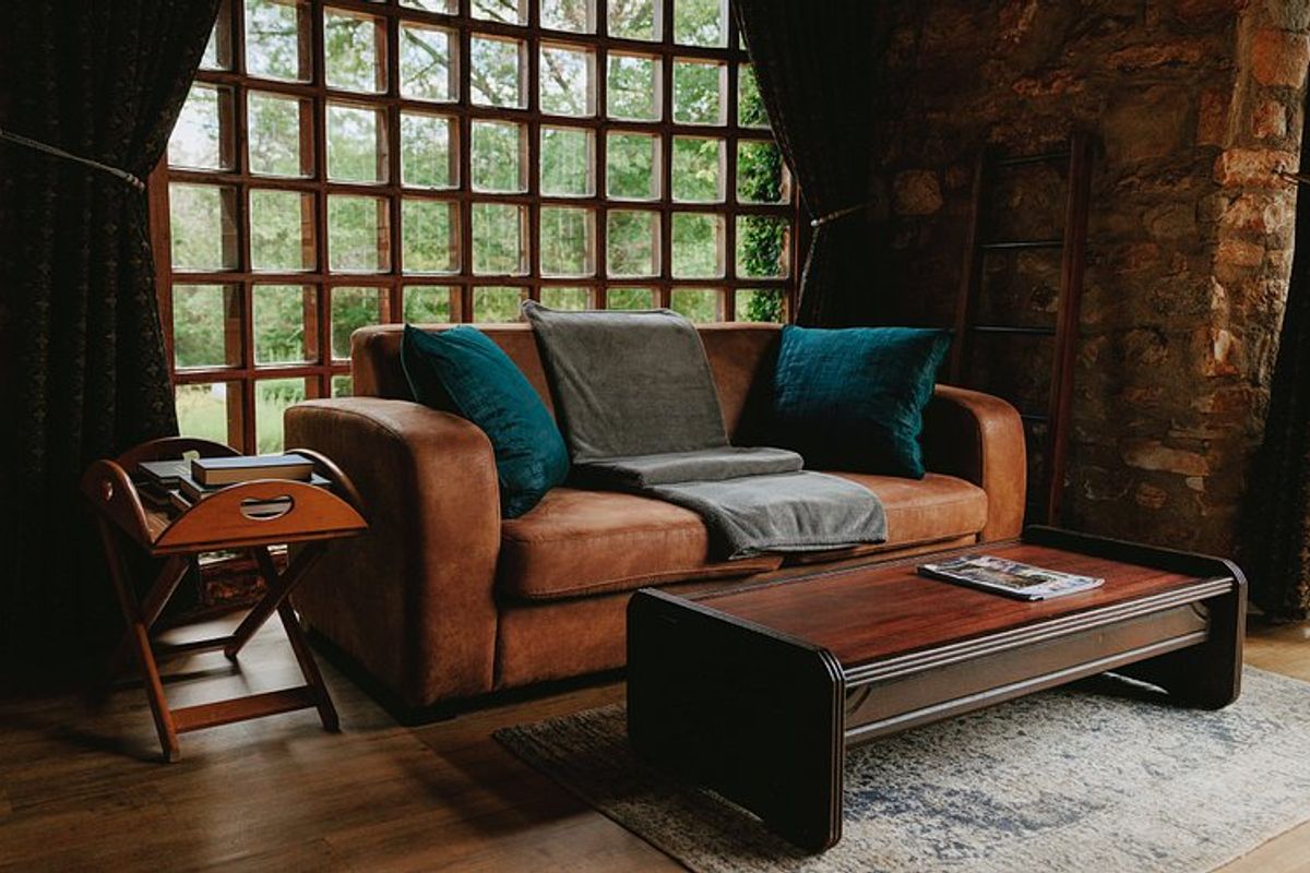 A cozy living room featuring rustic exposed stone walls and a large grid-patterned window that provides ample natural light.