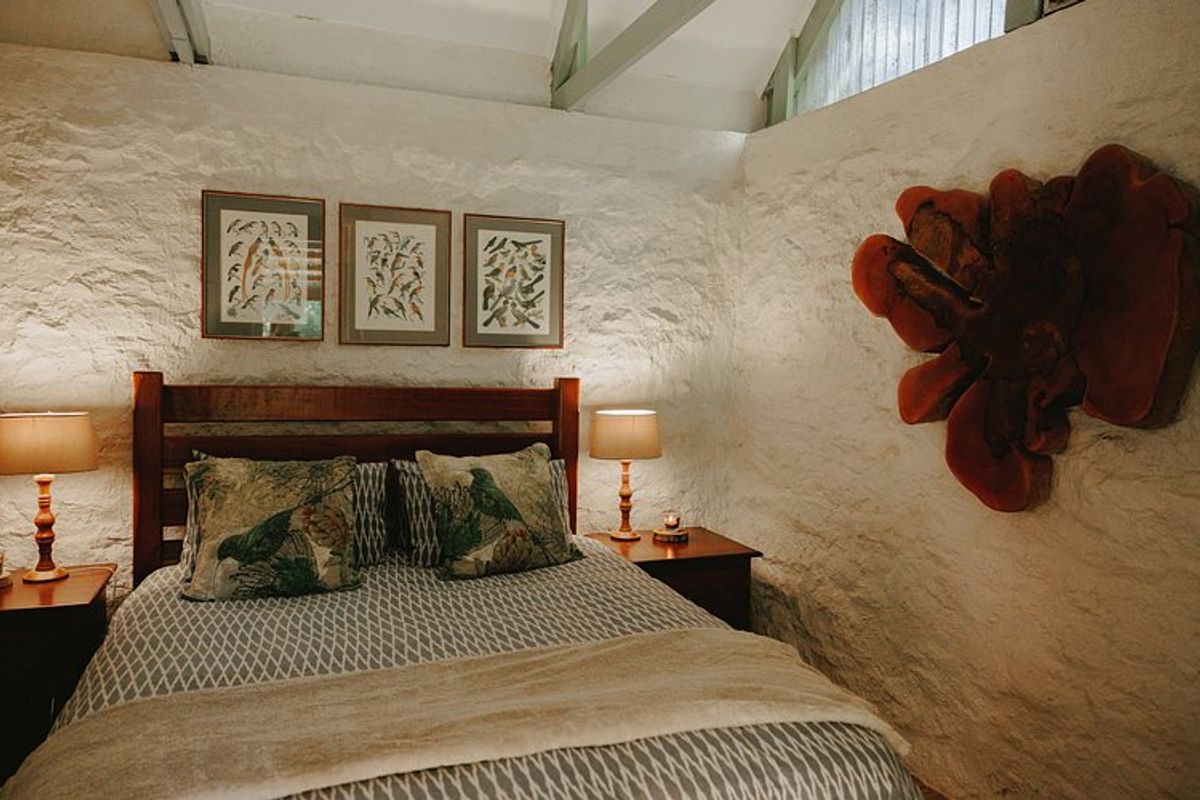 A cozy bedroom featuring rustic textured stone walls and exposed vaulted ceiling beams, creating a warm and inviting atmosphere.