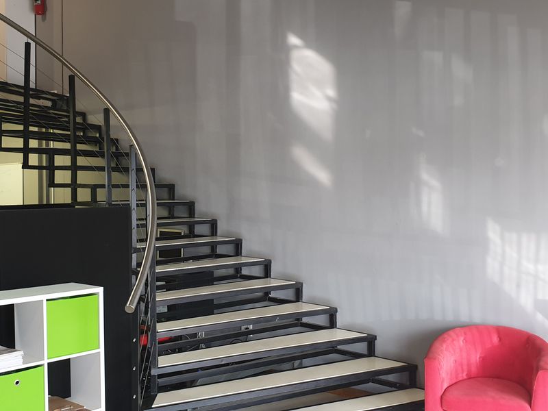 Modern retail entry area featuring a striking curved staircase with metal handrails leading to a mezzanine level.