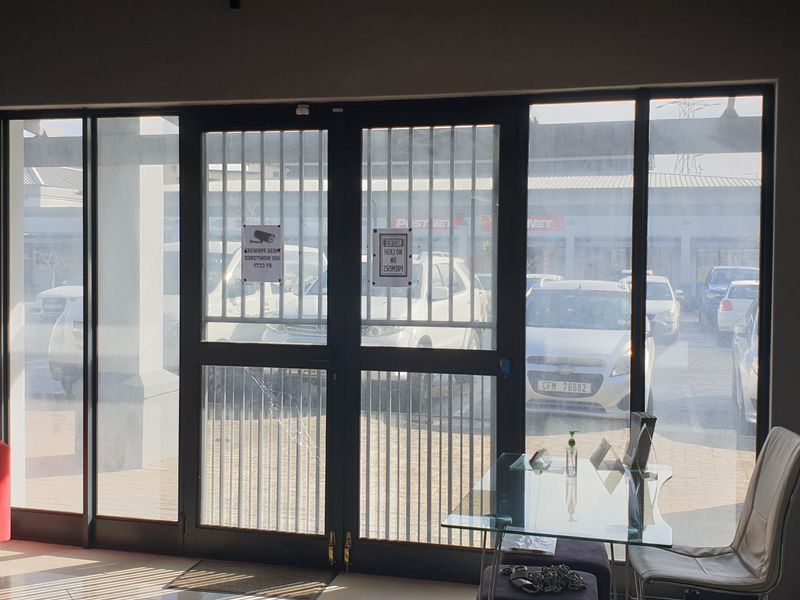 Entrance area featuring a secure glass door with security gate, tiled flooring, and wall-mounted fire safety equipment.