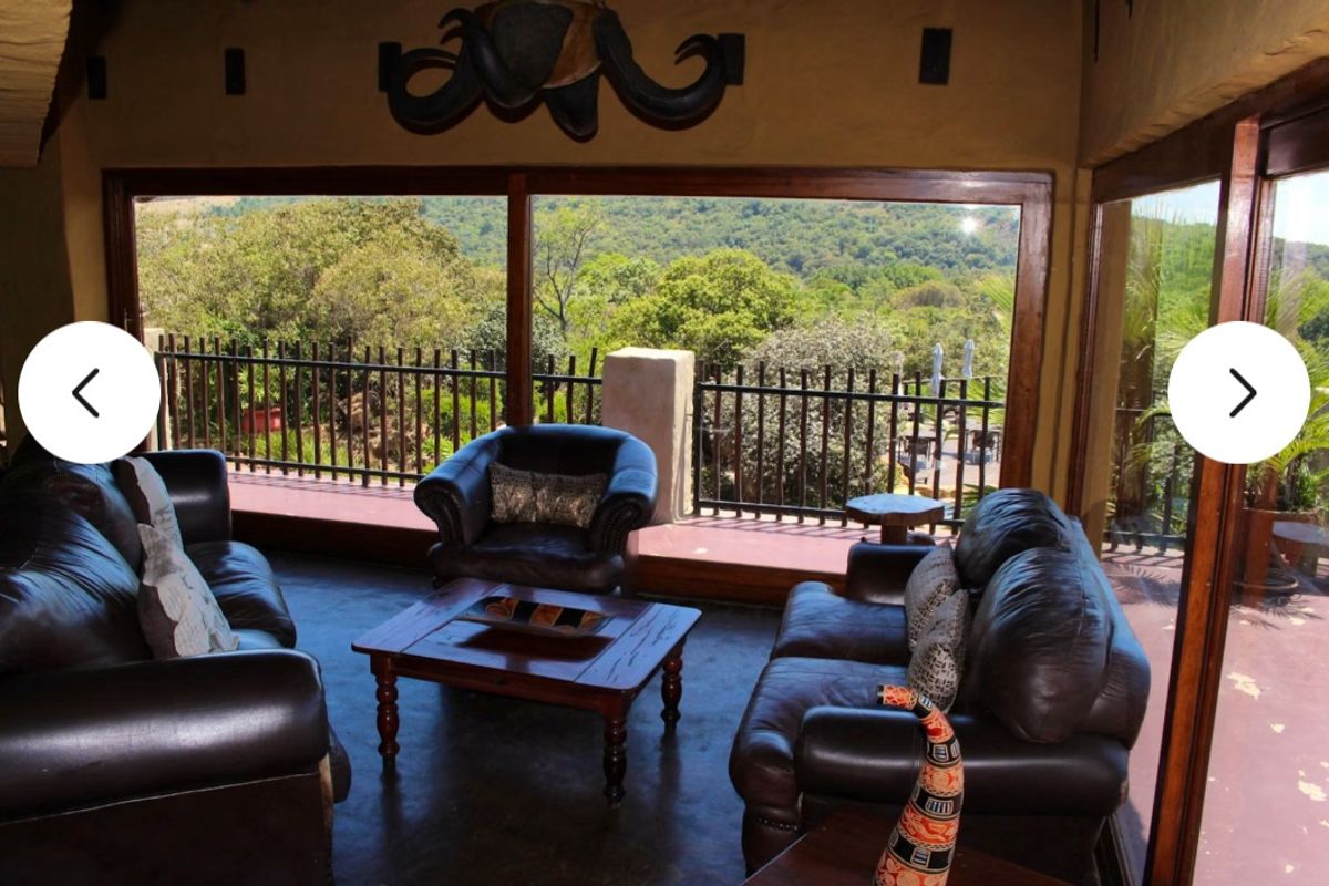 A spacious living area featuring large floor-to-ceiling windows that offer expansive views of the surrounding landscape and access to a private balcony.