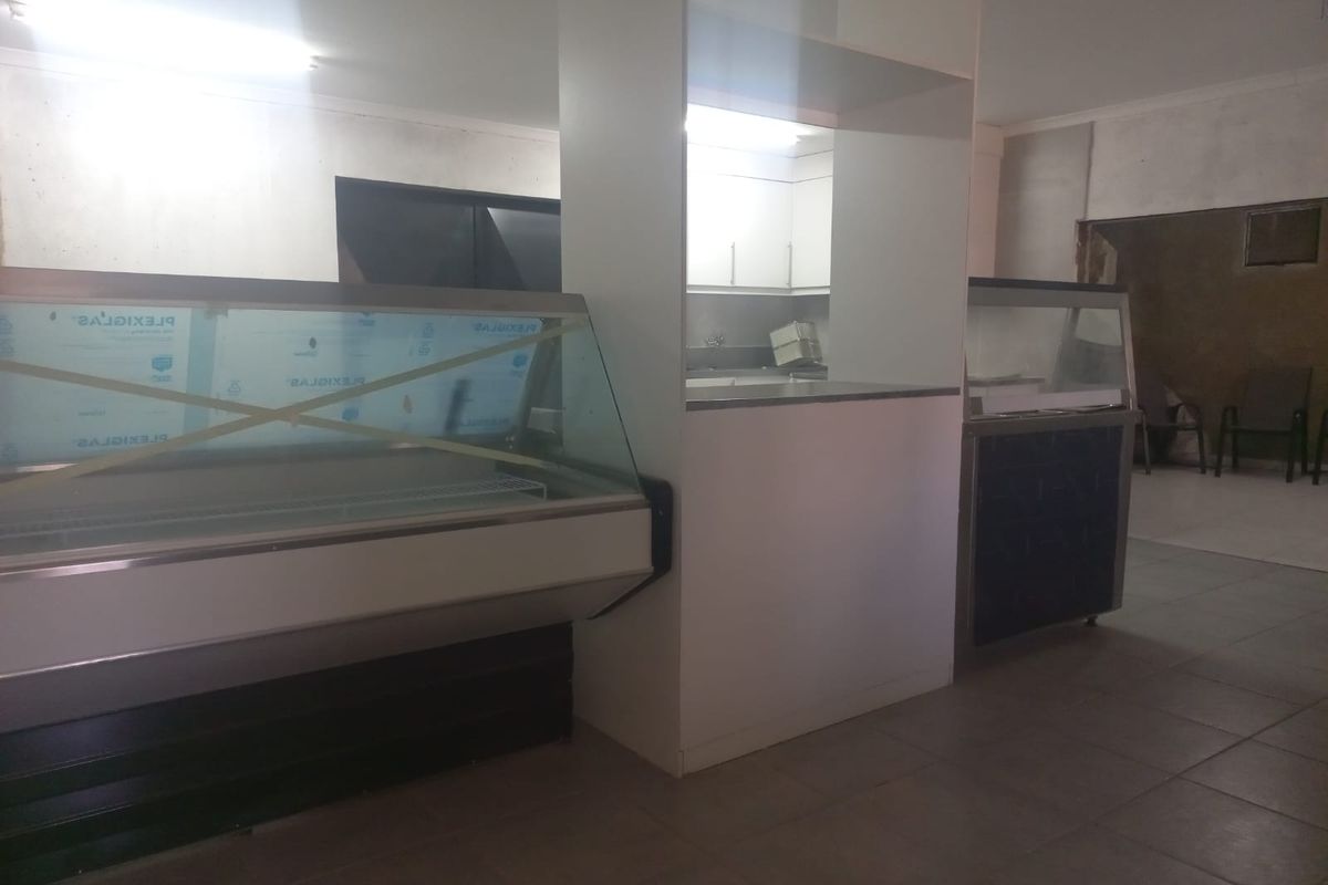 A commercial kitchen or service area featuring built-in cabinetry, tiled flooring, and service counters, currently in a state of renovation or partial completion.