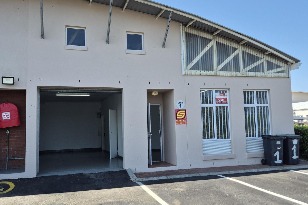 Front elevation of an industrial unit featuring a roller shutter door, pedestrian entrance, security bars, and dedicated asphalt parking space.