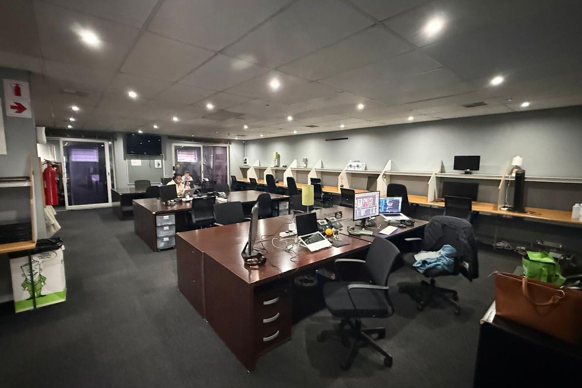 Spacious open-plan office area featuring recessed ceiling lighting, built-in desk partitions, and dark carpeting, suitable for a collaborative work environment.