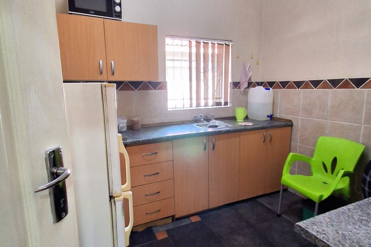 A compact kitchen area featuring built-in wooden cabinetry, a stainless steel sink, and tiled splashbacks.