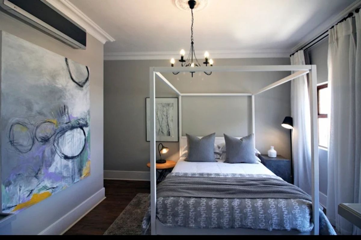 A well-appointed bedroom featuring crown molding, dark hardwood flooring, and a wall-mounted air conditioning unit.