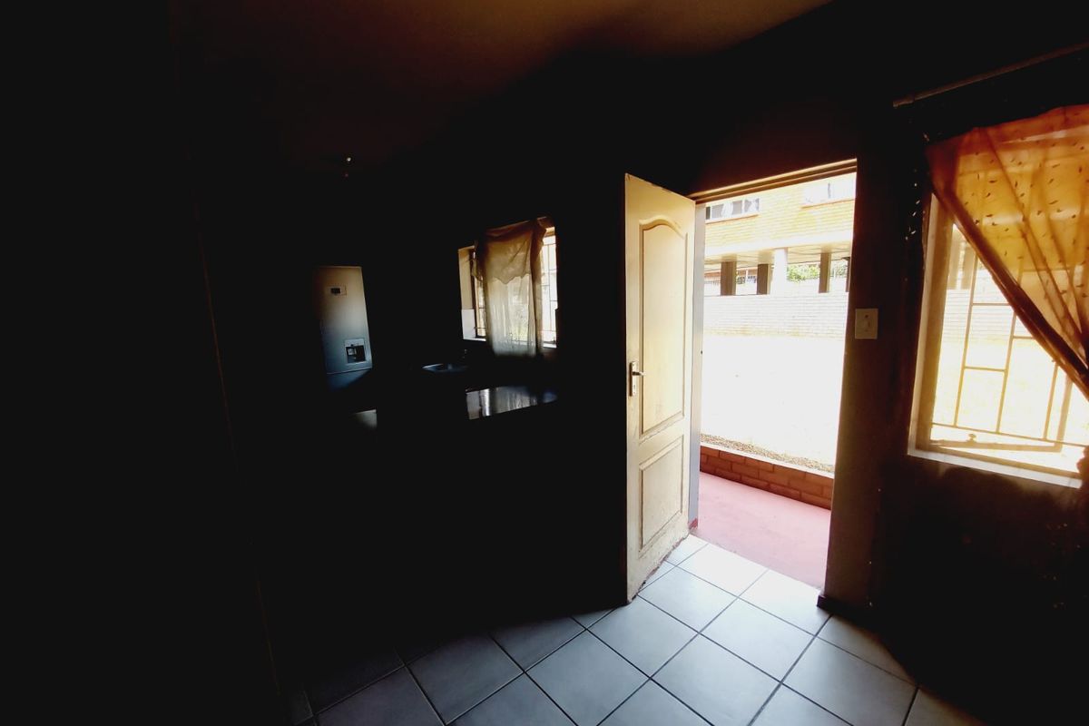 Interior view of a room with tiled flooring, leading out to an exterior area through a doorway.