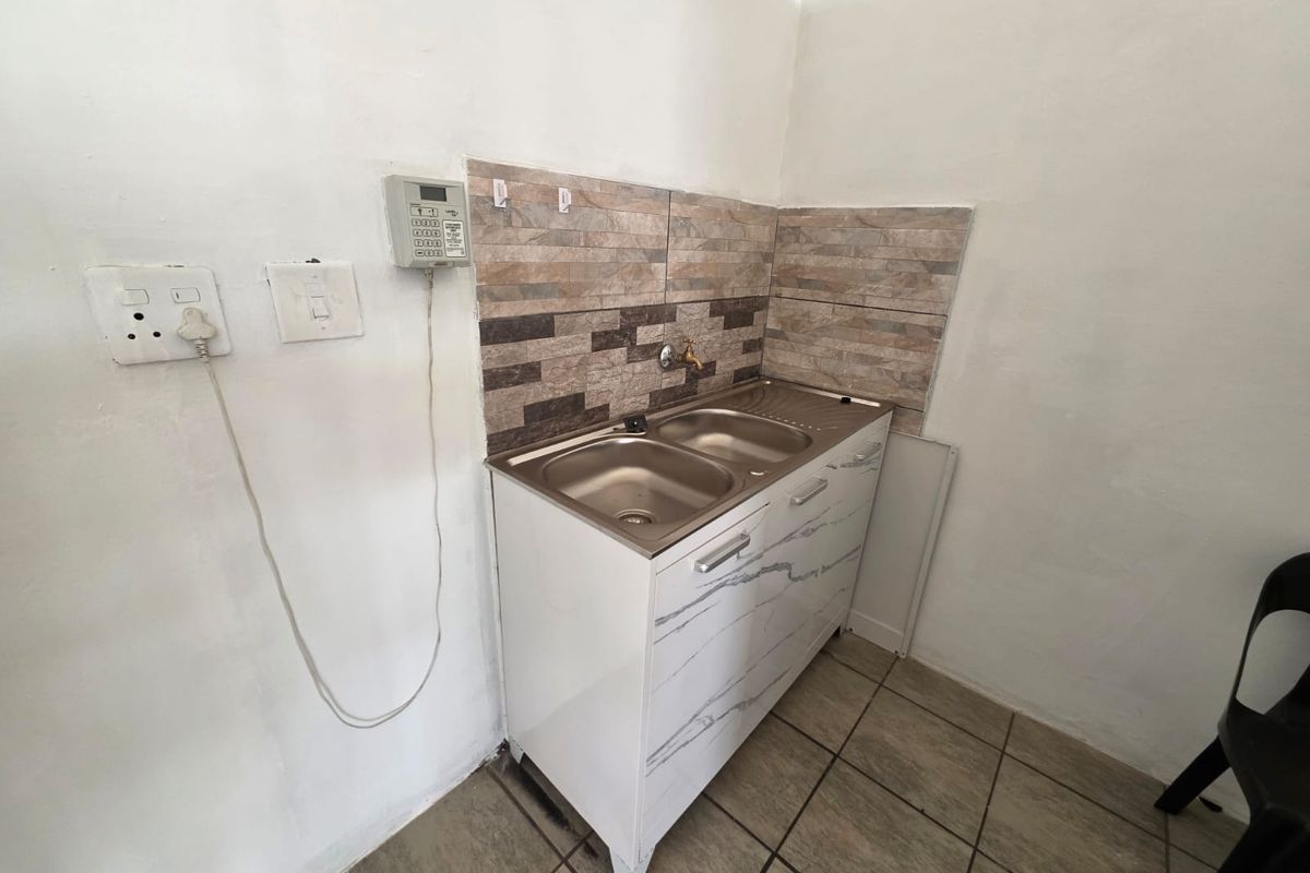 A functional scullery area featuring a stainless steel double sink, tiled splashback, and built-in cabinetry, suitable for utility or prep work.
