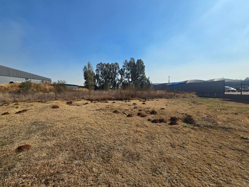 A view of a vacant commercial land plot featuring dry grass and uneven terrain, suitable for future development.