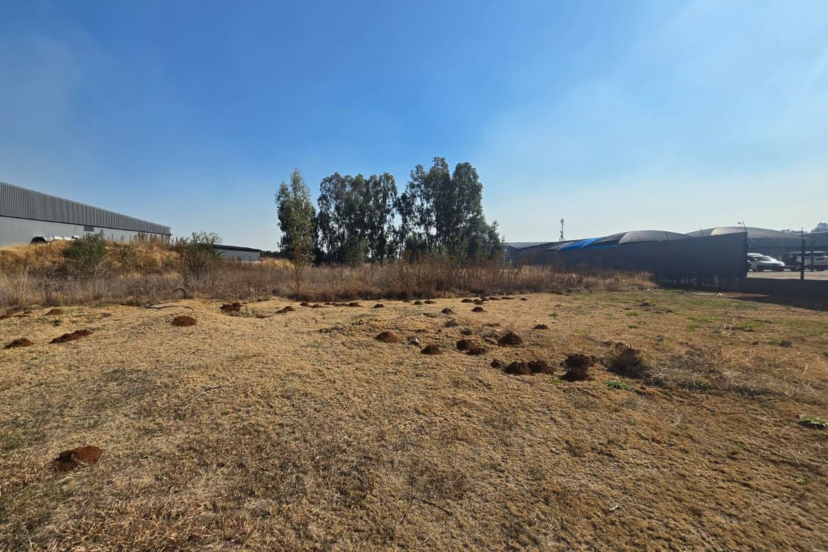 A view of a vacant commercial land plot featuring dry grass and uneven terrain, suitable for future development.