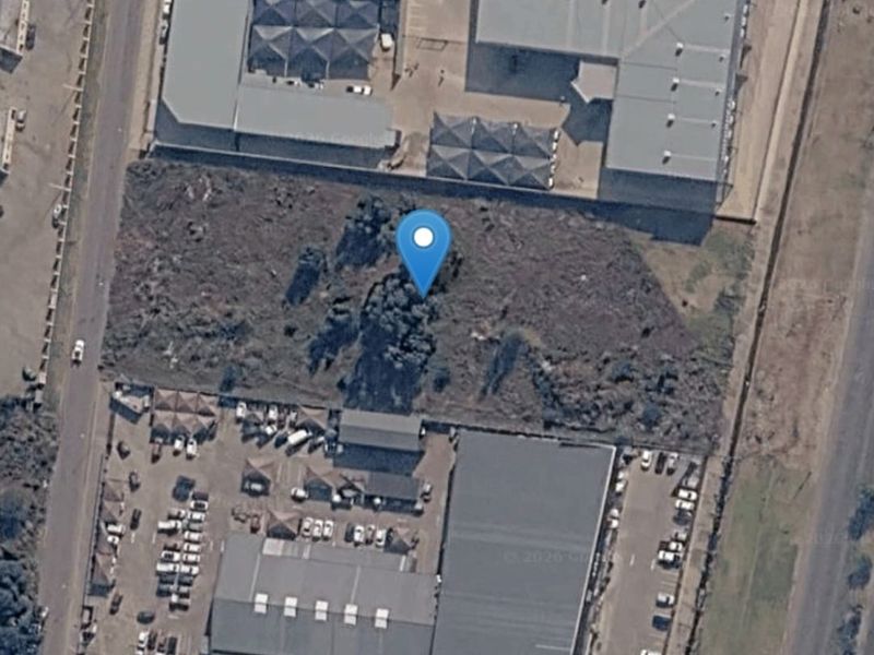 Aerial view of a vacant commercial land plot situated between established commercial warehouse and office developments.