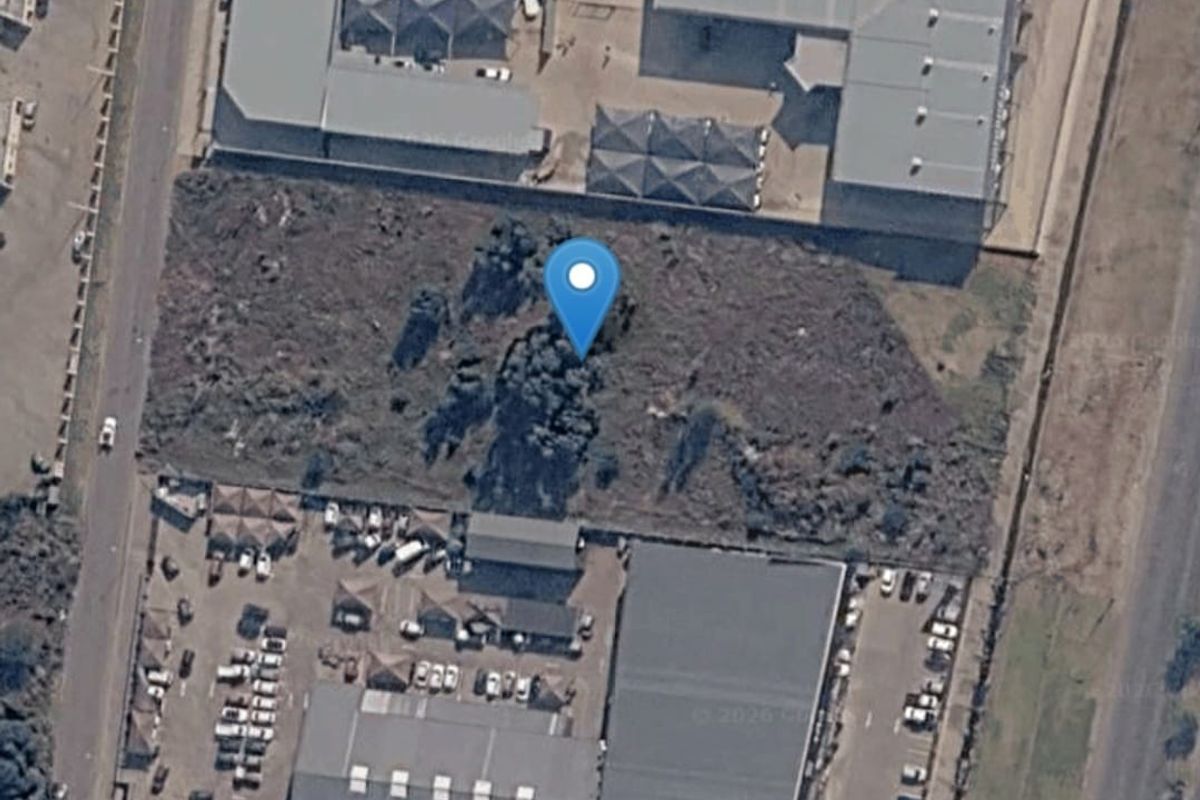 Aerial view of a vacant commercial land plot situated between established commercial warehouse and office developments.