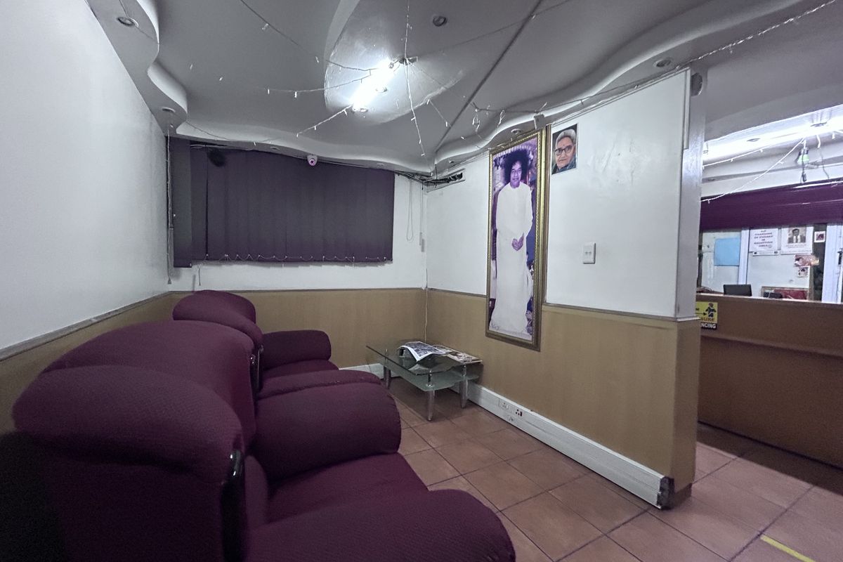 A waiting area or reception space featuring tiled flooring, recessed ceiling lighting, and a partition wall separating the main area from the service counter.