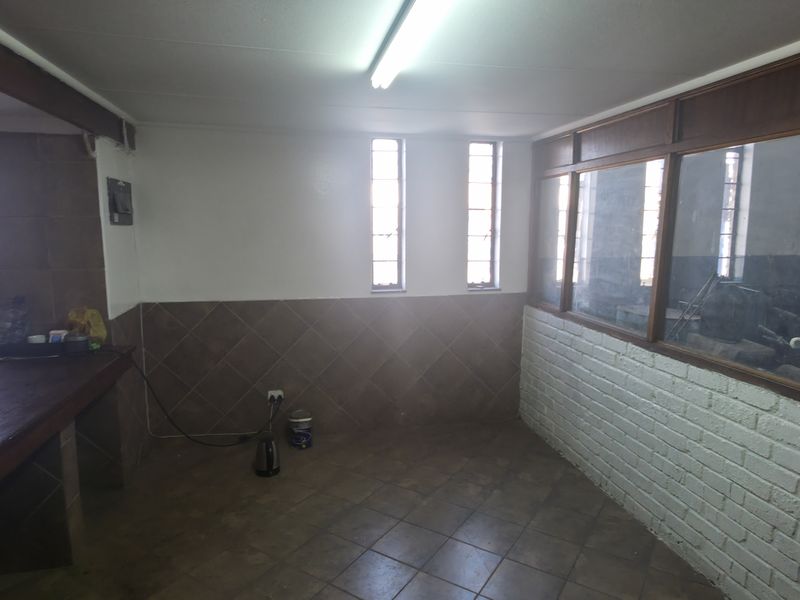 A functional utility space featuring tiled flooring, wall cladding, and an internal glass partition, suitable for storage or workshop use.