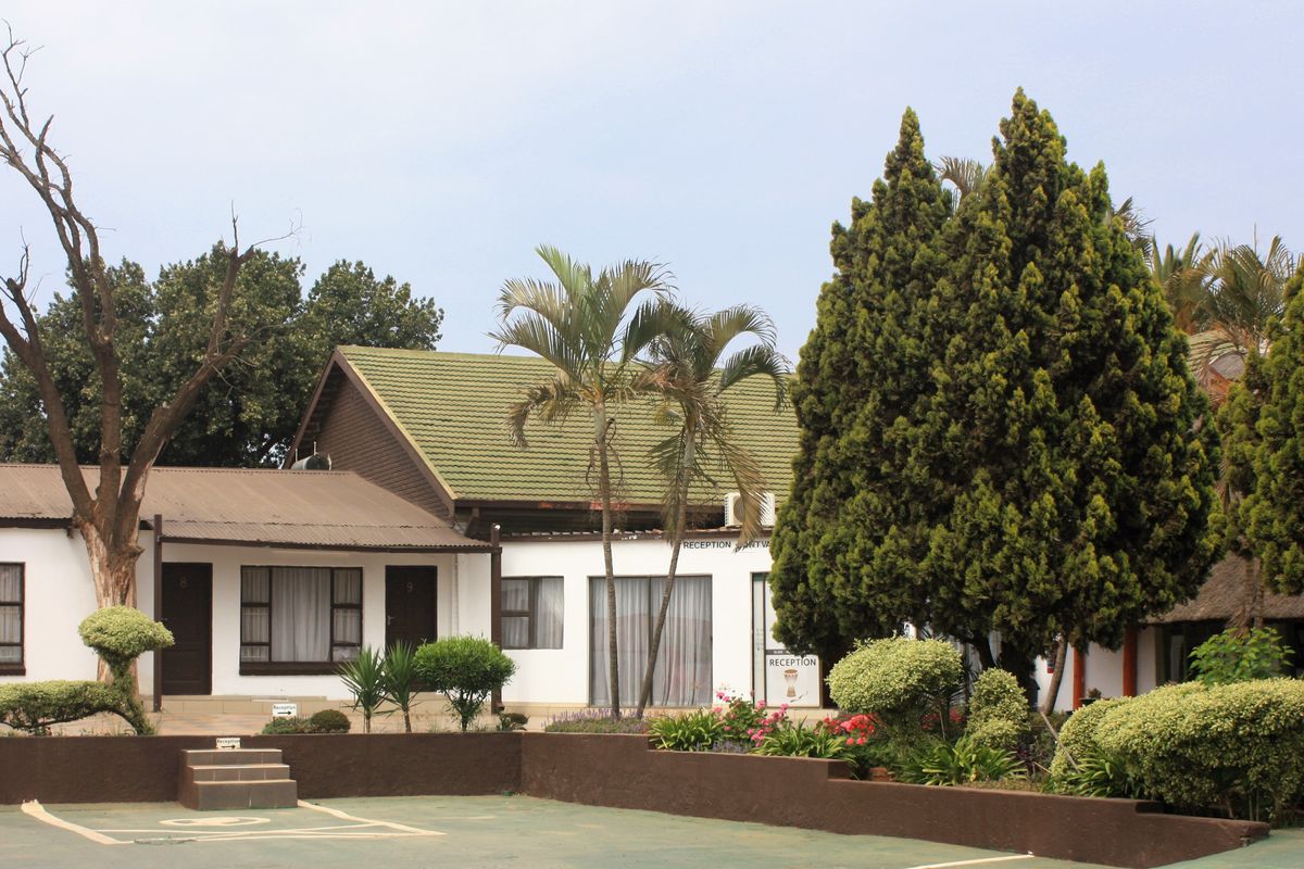 Front elevation of the property featuring a reception area, tiled roofing, and a paved driveway with established garden landscaping.