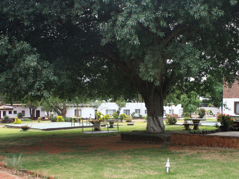 A spacious, well-maintained garden area featuring mature trees, expansive lawns, and established landscaping on a small holding property.