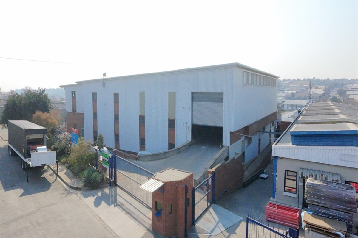 Aerial view of an industrial warehouse facility featuring a loading ramp, roller shutter door, and secure gated entrance.