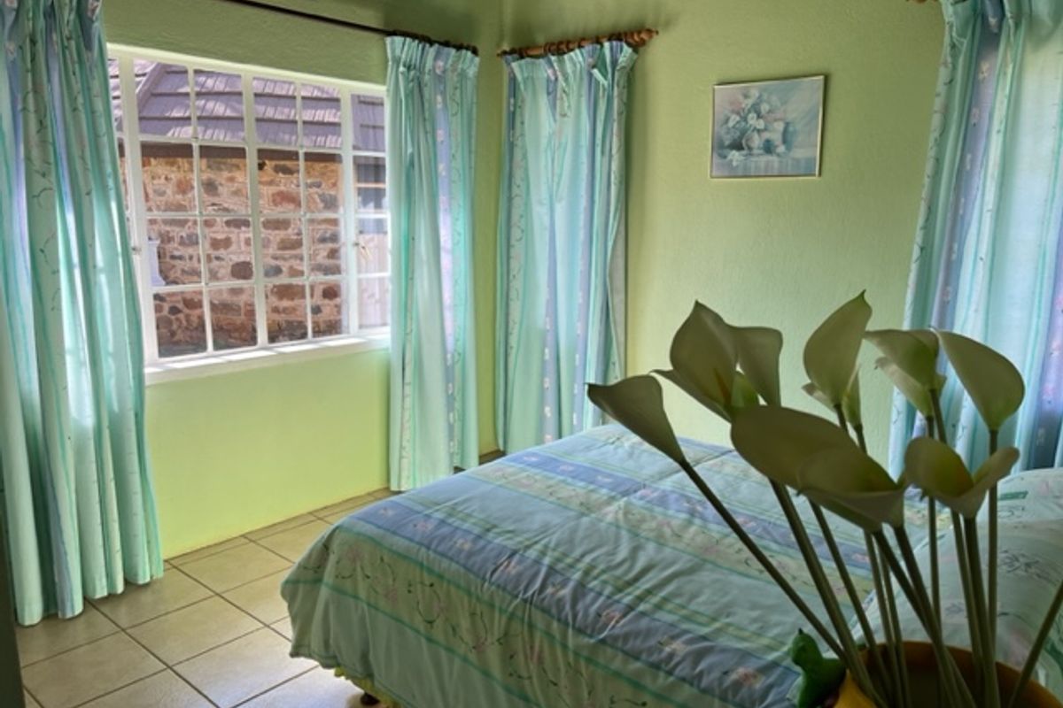A bedroom featuring tiled flooring and a multi-pane window with views of a stone exterior wall.