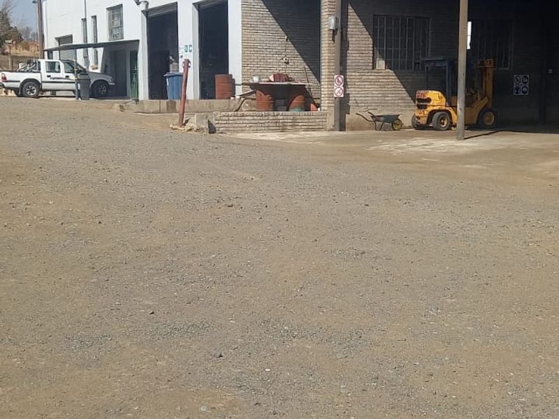 Commercial industrial property featuring a gravel yard, covered loading area, and multiple roller door access points.