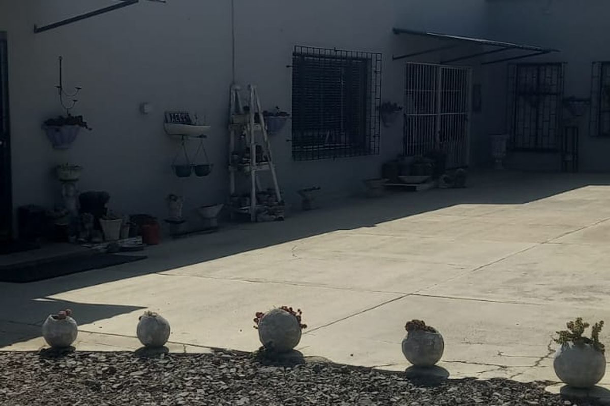 Rear exterior view of the commercial property featuring concrete paving, security bars on windows, and a roof-mounted water tank.