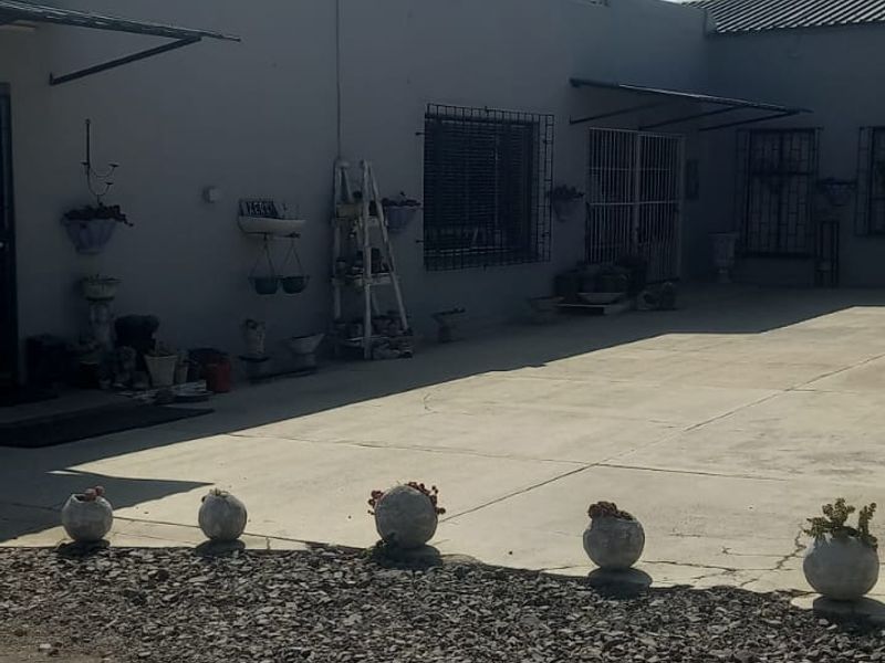 Rear exterior view of the commercial property featuring concrete paving, security bars on windows, and a roof-mounted water tank.