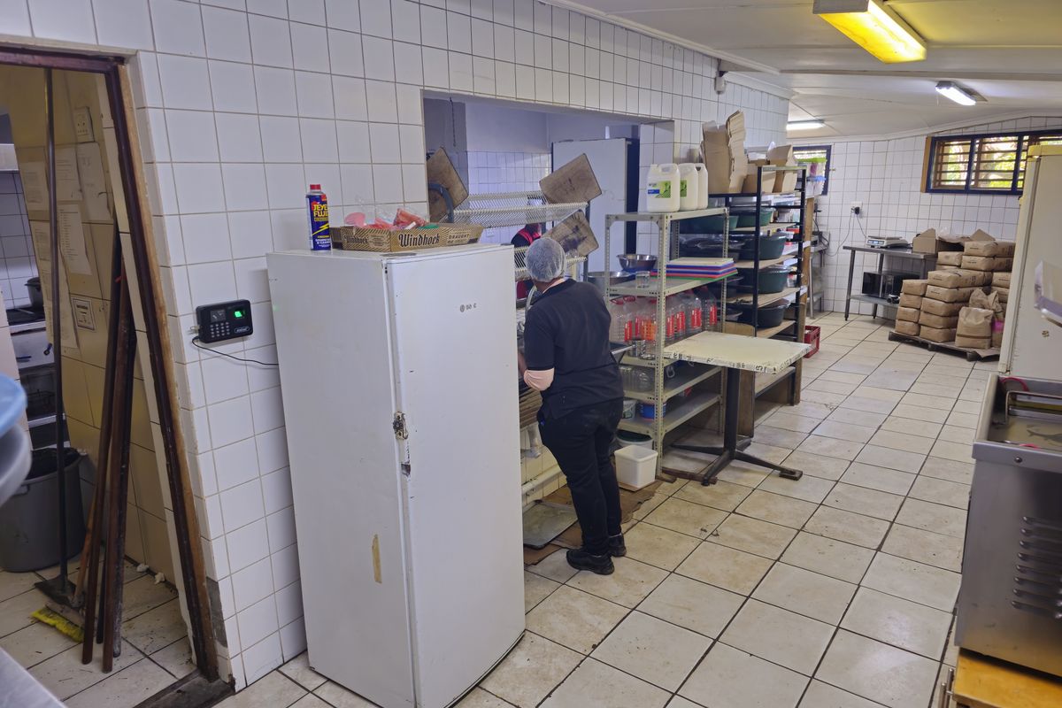 A functional commercial kitchen area featuring tiled walls and flooring, stainless steel shelving, and integrated food preparation zones for restaurant operations.