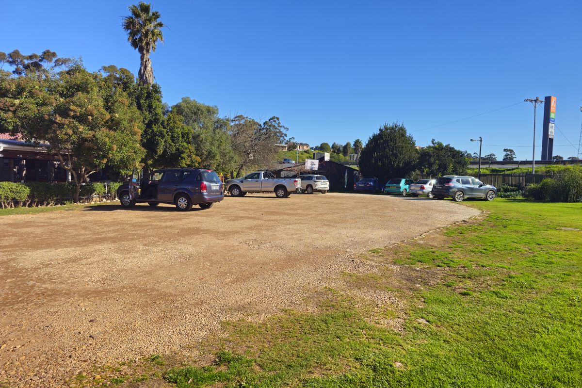 An expansive outdoor gravel parking area serving the restaurant property, featuring surrounding greenery and mature trees.