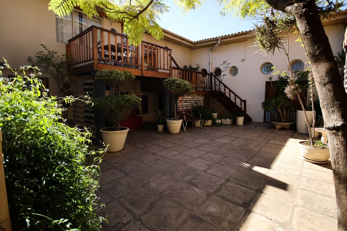 A spacious rear courtyard featuring paved flooring, a raised timber deck with staircase access, and circular architectural windows.