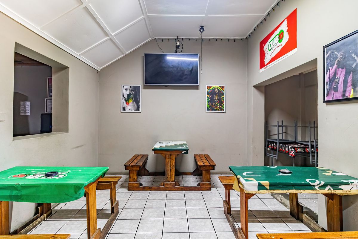 A commercial bar or lounge area featuring tiled flooring, a vaulted ceiling, and built-in seating arrangements suitable for a social or hospitality setting.