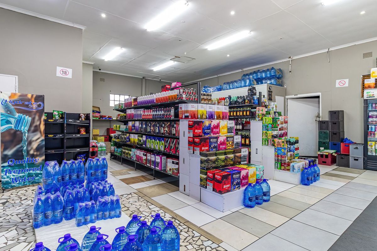 Commercial retail space featuring tiled flooring, recessed ceiling lighting, and extensive built-in shelving units for product display.
