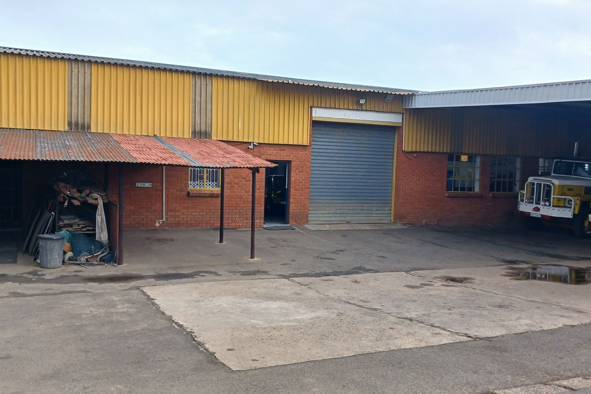 Commercial industrial property featuring a brick and corrugated metal facade, roller shutter door, and a covered loading bay area with concrete hardstand.