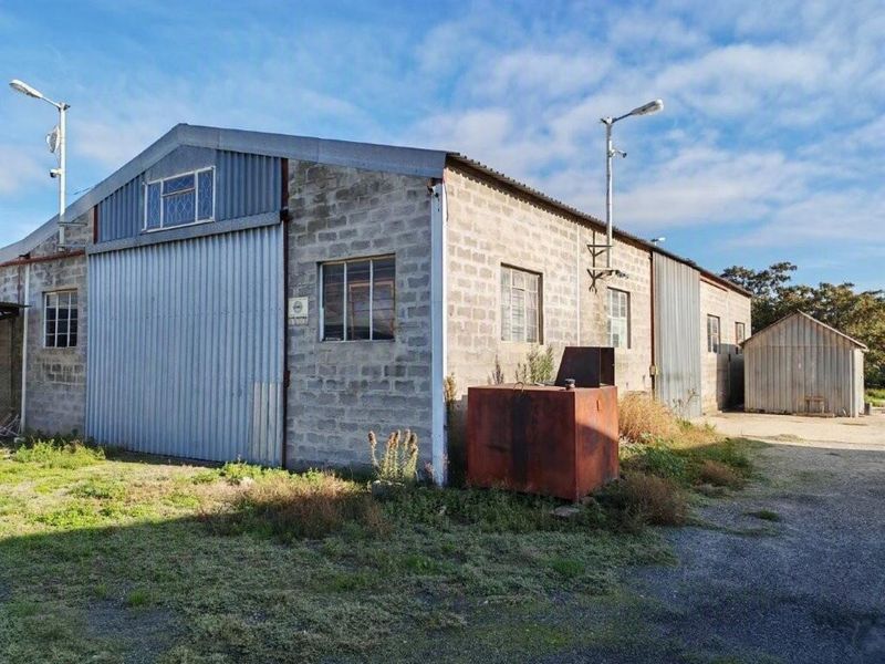 Rear view of a commercial industrial warehouse featuring concrete block construction, corrugated metal siding, and large sliding access doors.