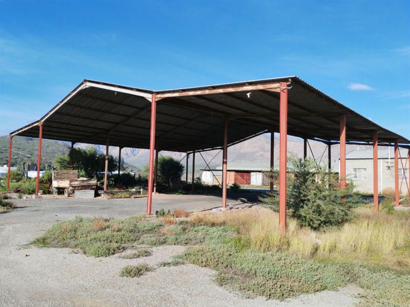 Large open-sided steel-framed utility structure with a corrugated metal roof, suitable for storage or industrial use, set on a concrete base.