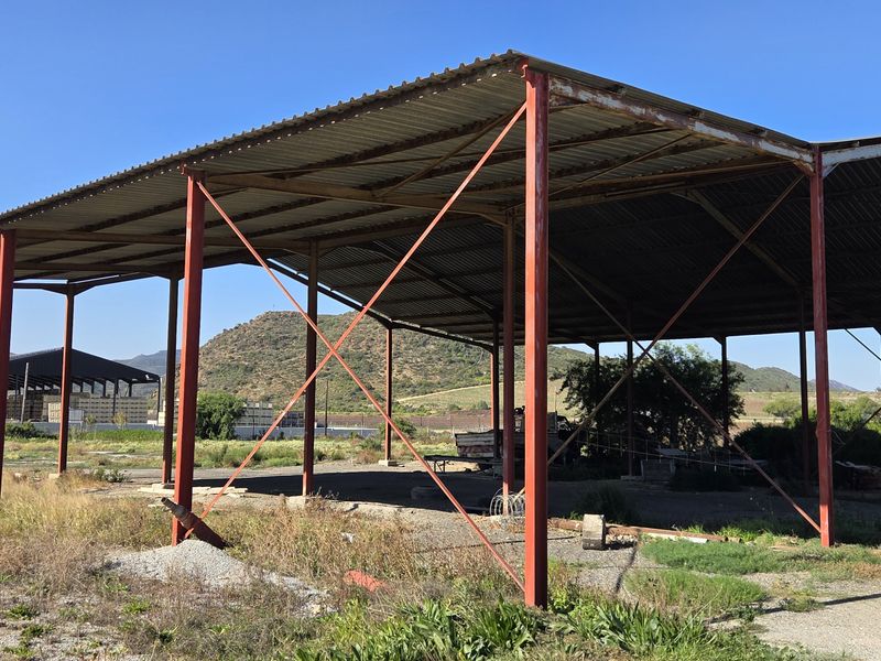 Large open-sided industrial steel structure with a corrugated metal roof, suitable for storage or covered outdoor utility use.