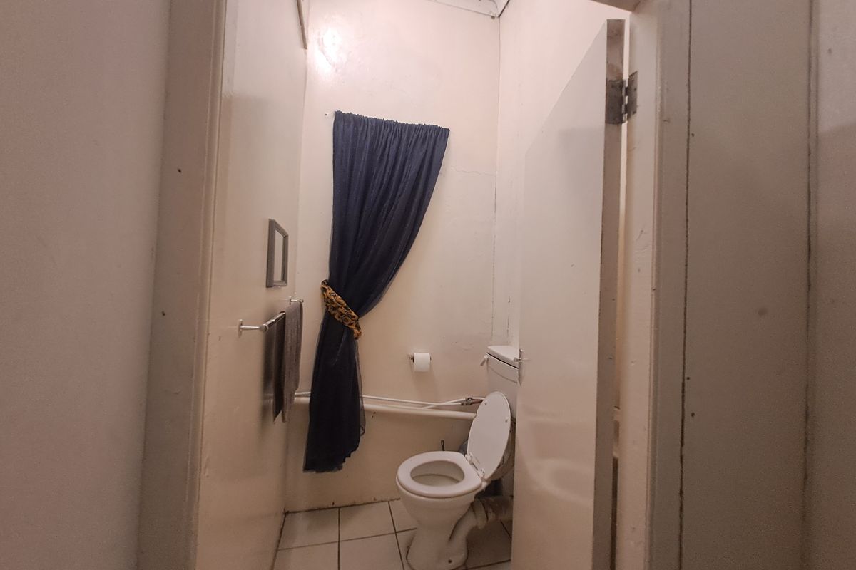 A small, dated bathroom featuring a standard toilet and tiled flooring, currently in need of cosmetic updates and maintenance.