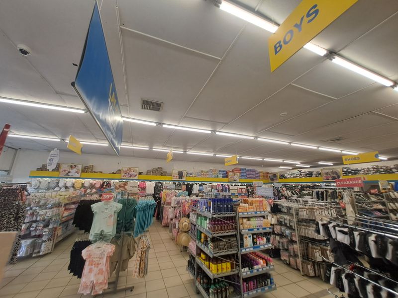 Interior view of a commercial retail space featuring tiled flooring, suspended ceiling tiles, and overhead fluorescent lighting.