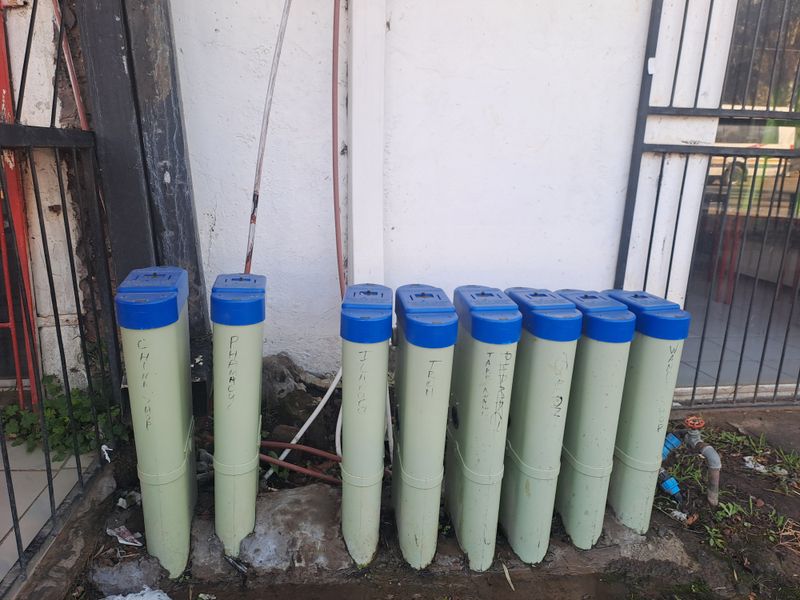 A row of external utility meters mounted against a commercial building wall with an adjacent outdoor water tap.
