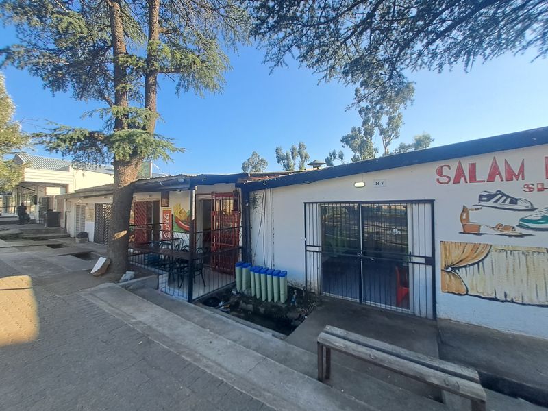 Commercial storefront exterior featuring painted facade, security gates, and concrete steps, showing signs of wear and weathering.