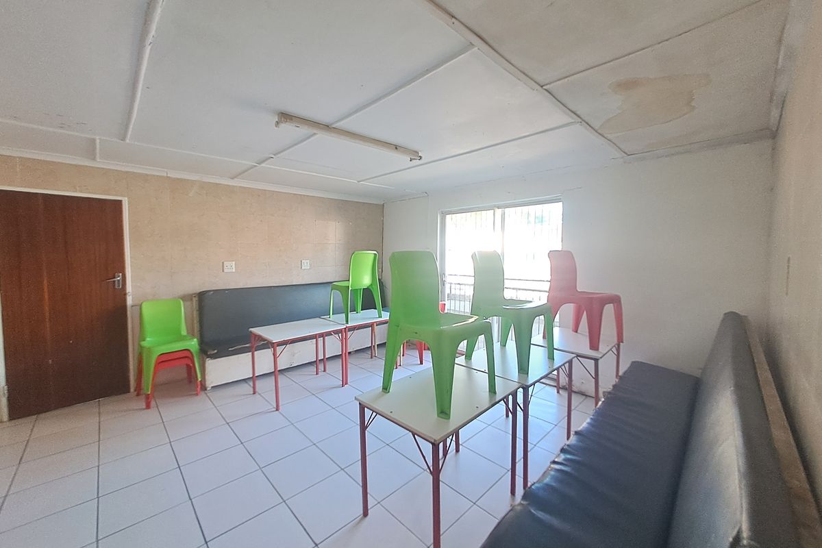 A commercial interior space featuring tiled flooring, built-in bench seating, and a suspended ceiling with visible water damage.