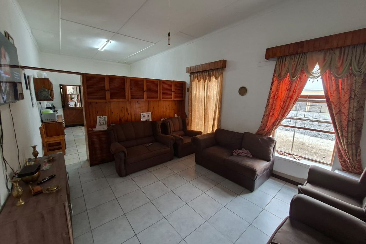 A spacious living area featuring tiled flooring, built-in wooden cabinetry, and large windows with natural light, providing a functional and comfortable space.