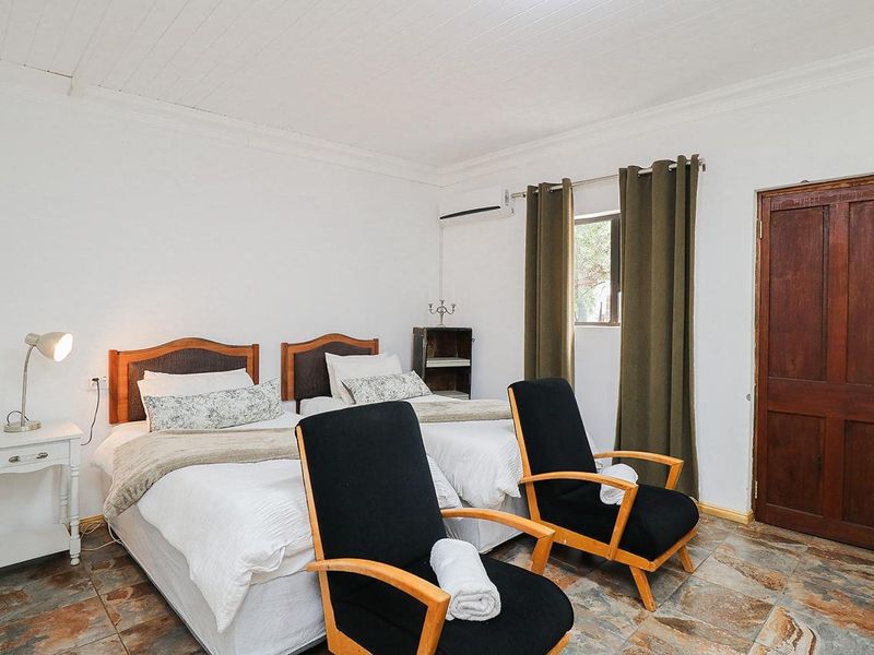 A guest bedroom featuring tiled flooring, a tongue and groove ceiling, and a wall-mounted air conditioning unit.