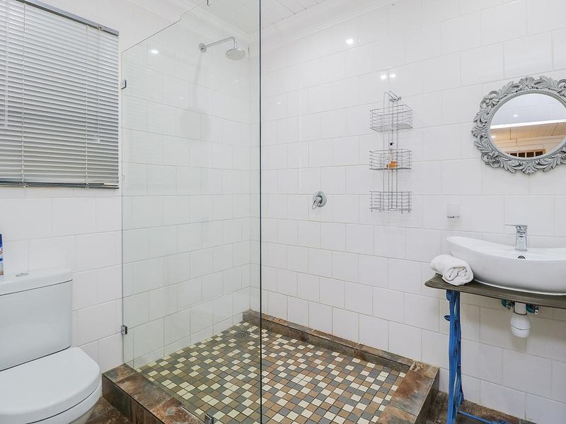 Modern bathroom featuring a walk-in shower with glass screen, subway tiled walls, mosaic floor tiling, and a contemporary vessel sink.