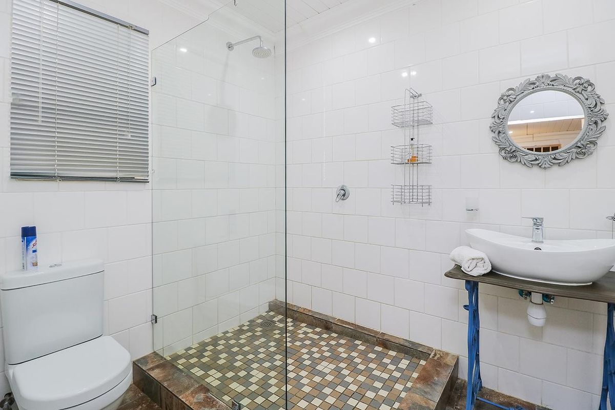Modern bathroom featuring a walk-in shower with glass screen, subway tiled walls, mosaic floor tiling, and a contemporary vessel sink.
