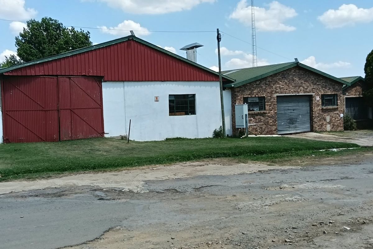 Commercial property exterior featuring a combination of brick and metal cladding, including a large sliding barn door and a roller shutter access point.