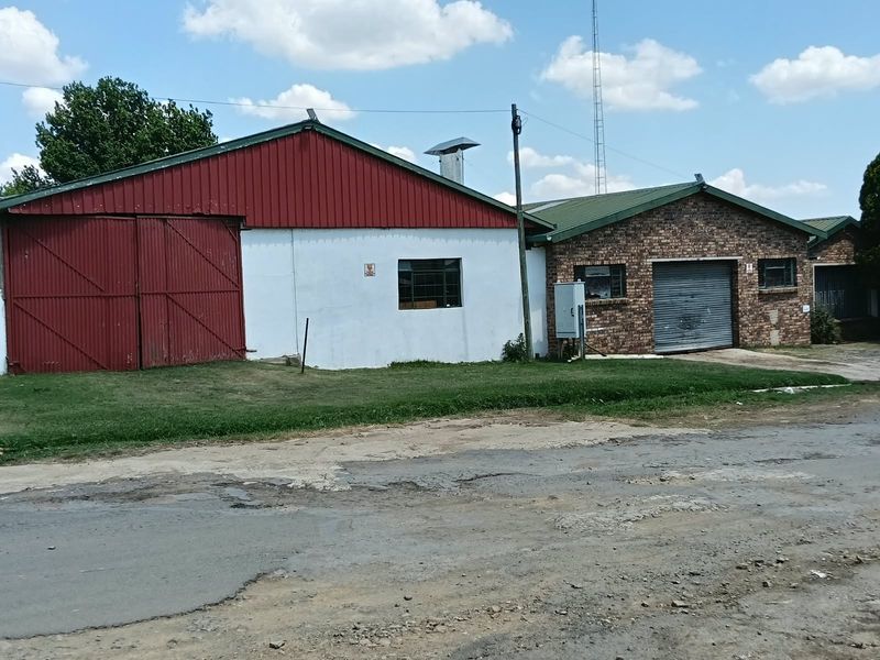Commercial property exterior featuring a combination of brick and metal cladding, including a large sliding barn door and a roller shutter access point.