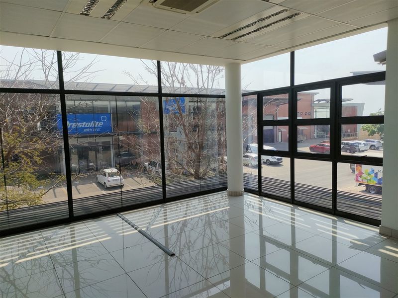 Bright and modern office space featuring expansive floor-to-ceiling windows, ceramic tile flooring, and a clean, professional suspended ceiling design.