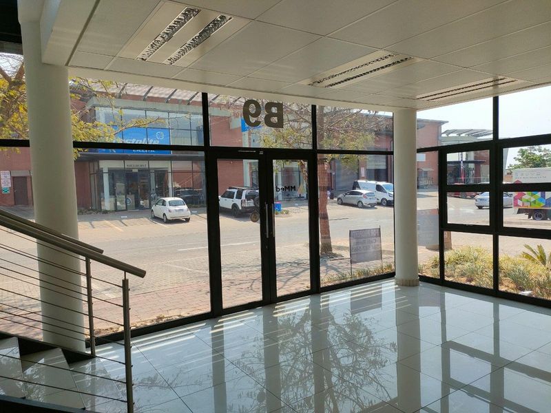 Bright and modern industrial entrance lobby featuring floor-to-ceiling glass windows, polished tiled flooring, and a clean, open-plan layout.