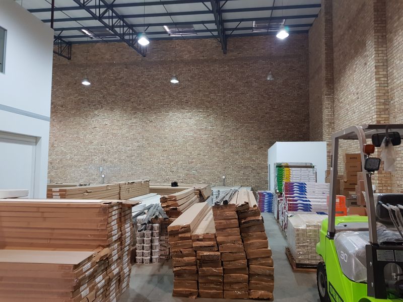 Spacious industrial warehouse unit featuring high ceilings with exposed steel trusses, brick wall finishes, and durable concrete flooring.
