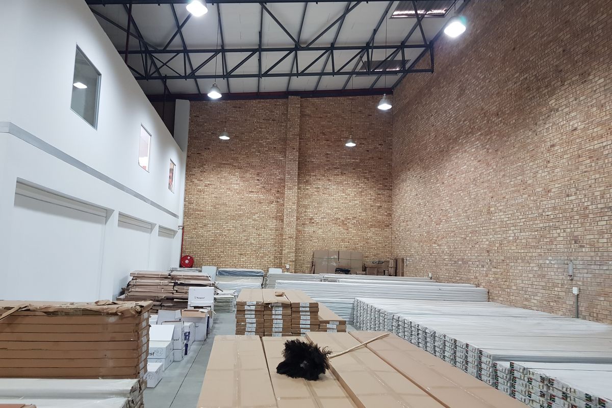 Spacious industrial warehouse unit featuring high ceilings with exposed steel trusses, brick wall finishes, and concrete flooring, suitable for storage or light manufacturing.