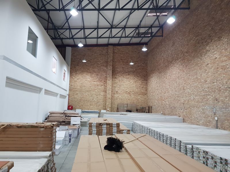 Spacious industrial warehouse unit featuring high ceilings with exposed steel trusses, brick wall finishes, and concrete flooring, suitable for storage or light manufacturing.